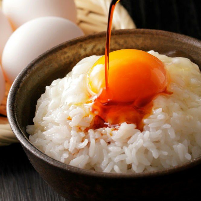 Shoyu being poured into a bowl of egg and rice
