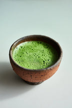 Ceramic bowl with green matcha tea on a light background