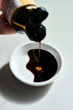 Kaneyoshi Kioke Shoyu pouring into a white dish on a gray background.