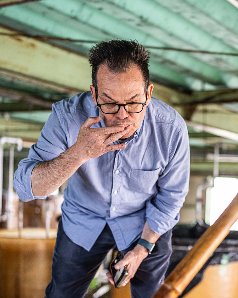 Henry in a blue shirt and glasses tasting shoyu out of a kioke barrel