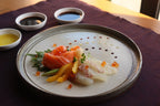 Plated dish of sashimi with garnishes on a textured surface