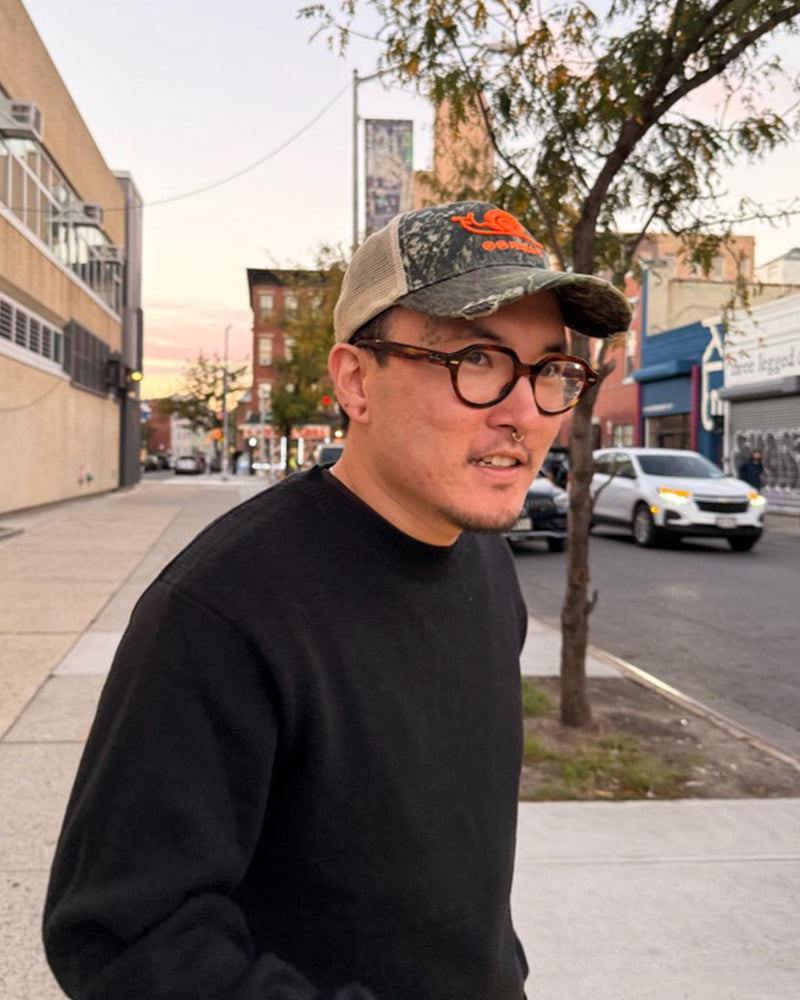 Jarin wearing a cap and glasses on a city street