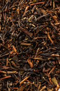 A close-up of loose Oishi Farm black tea leaves, showing a mix of dark brown twisted leaves and lighter stems with a coarse, uneven texture characteristic of roasted Japanese black tea.
