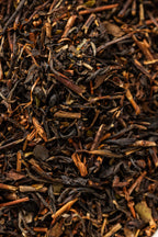 A close-up of loose Oishi Farm black tea leaves, showing a mix of dark brown twisted leaves and lighter stems with a coarse, uneven texture characteristic of roasted Japanese black tea.
