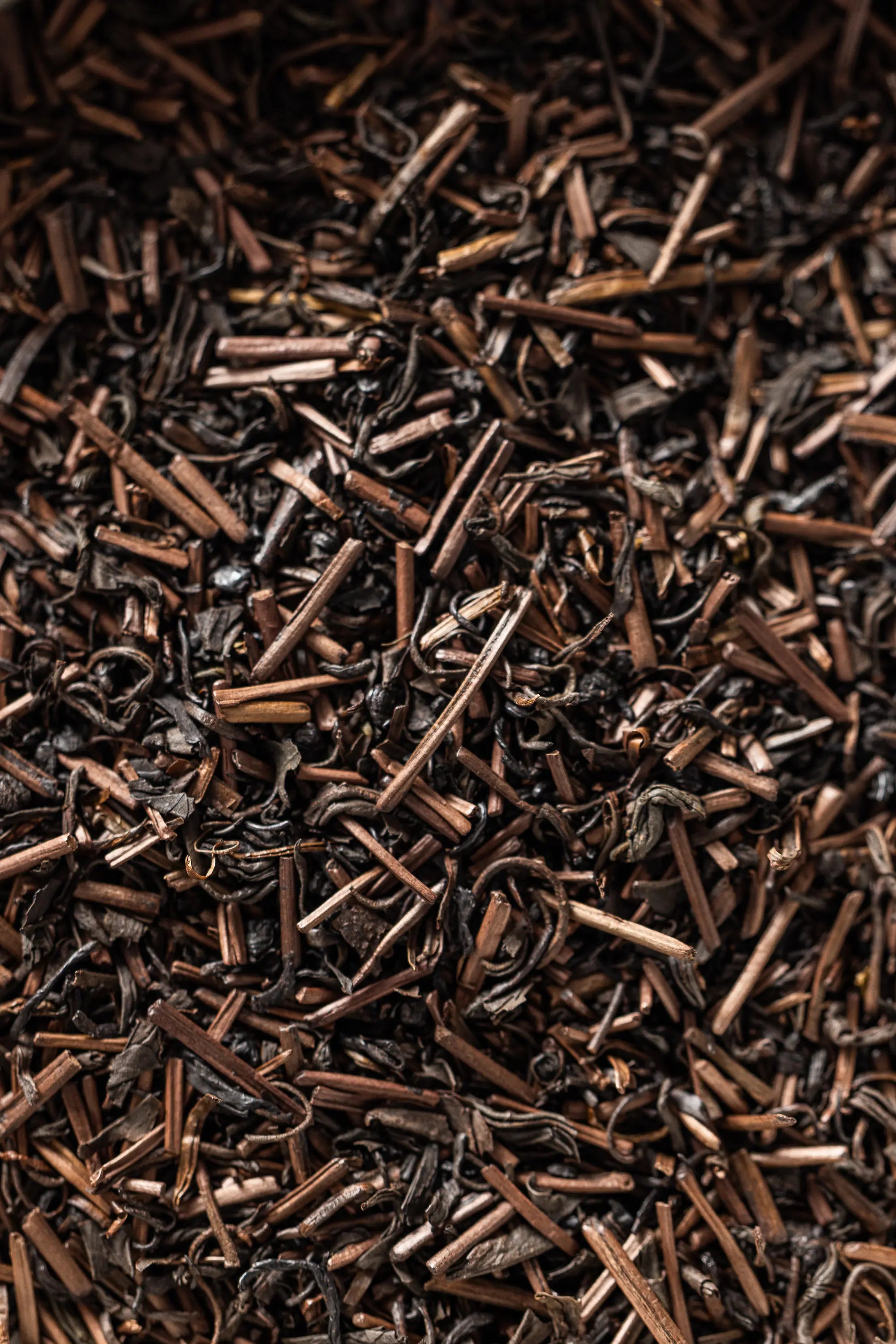 A close-up of Oyama Seicha hojicha, showing roasted brown tea leaves and stems with a mix of curled and twig-like pieces.