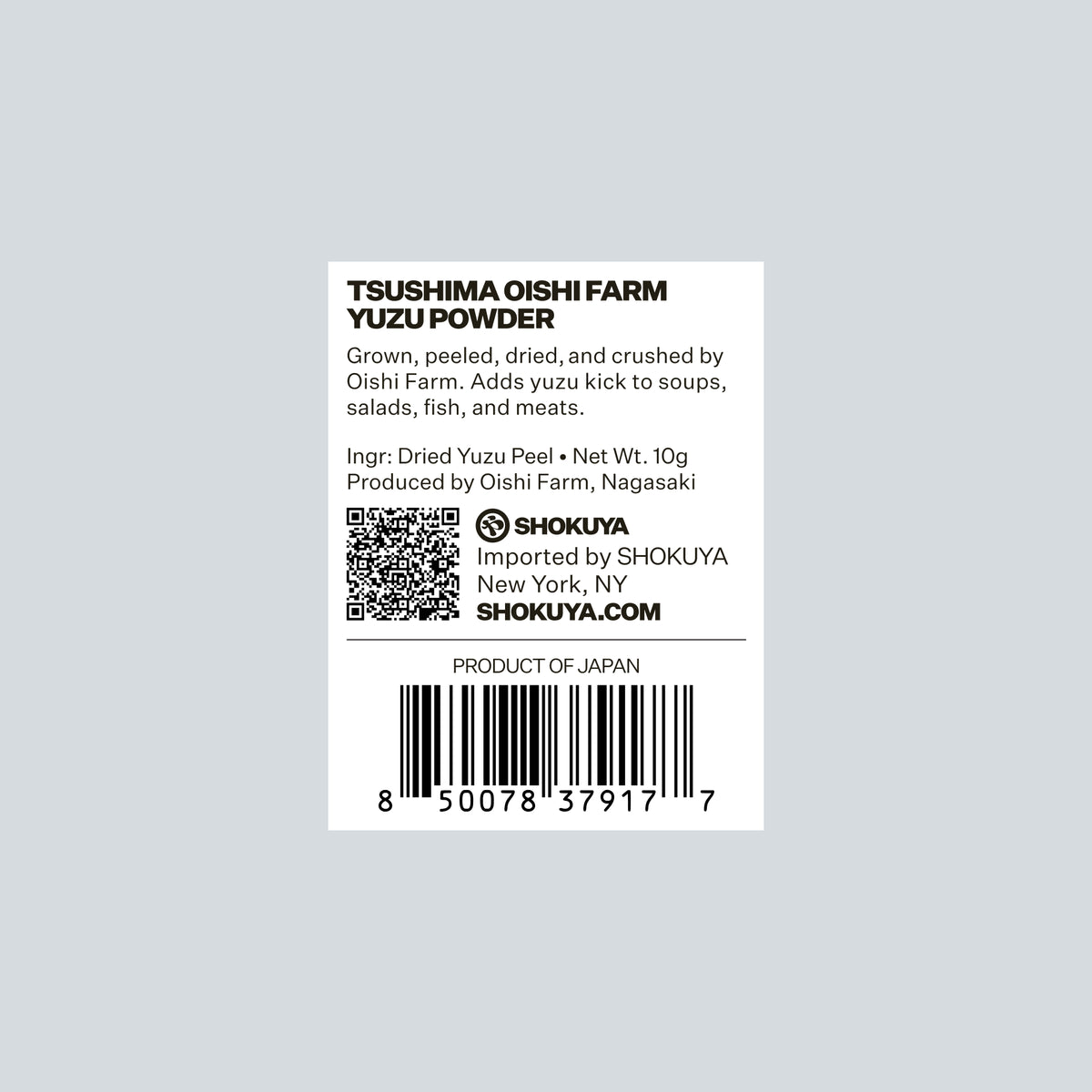 A white rectangular product label for Oishi Farm Yuzu Powder, featuring black text, a QR code, and a barcode on a light gray background. The label includes Shokuya branding and product details.