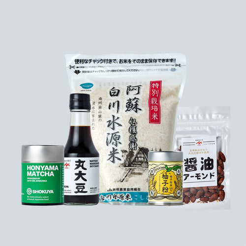Collection of Japanese food products including soy sauce, rice, and other packaged items on a light gray background.