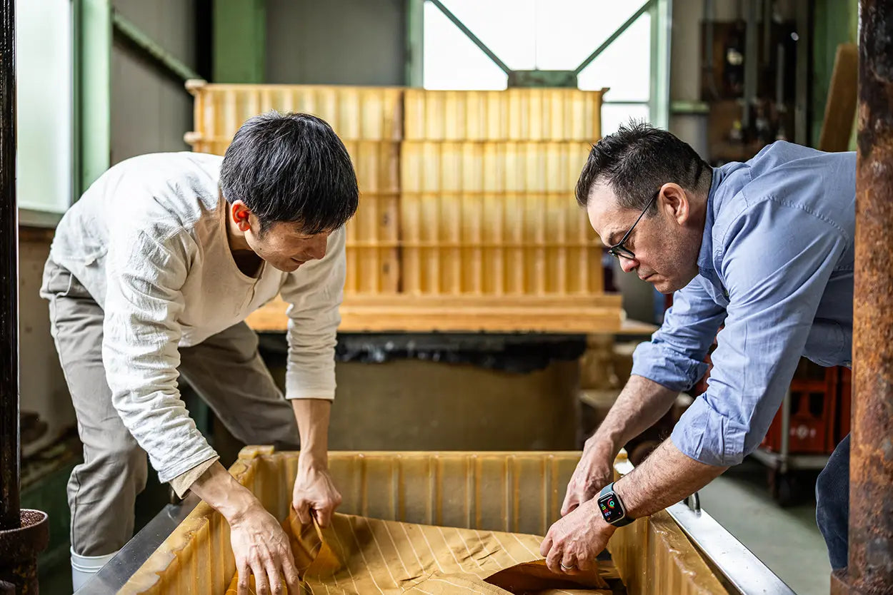 Two men working together on a wooden surface in an indoor setting.