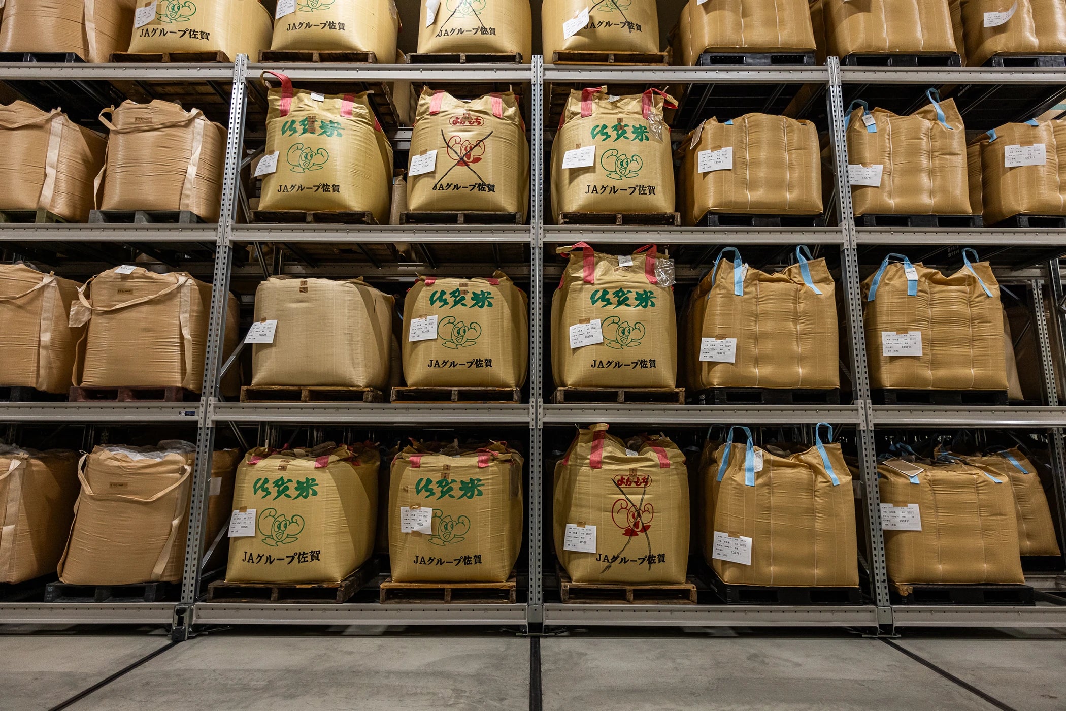 Kanegae rice warehouse shelving stacked with bulk Japanese Saga rice sacks on pallets.