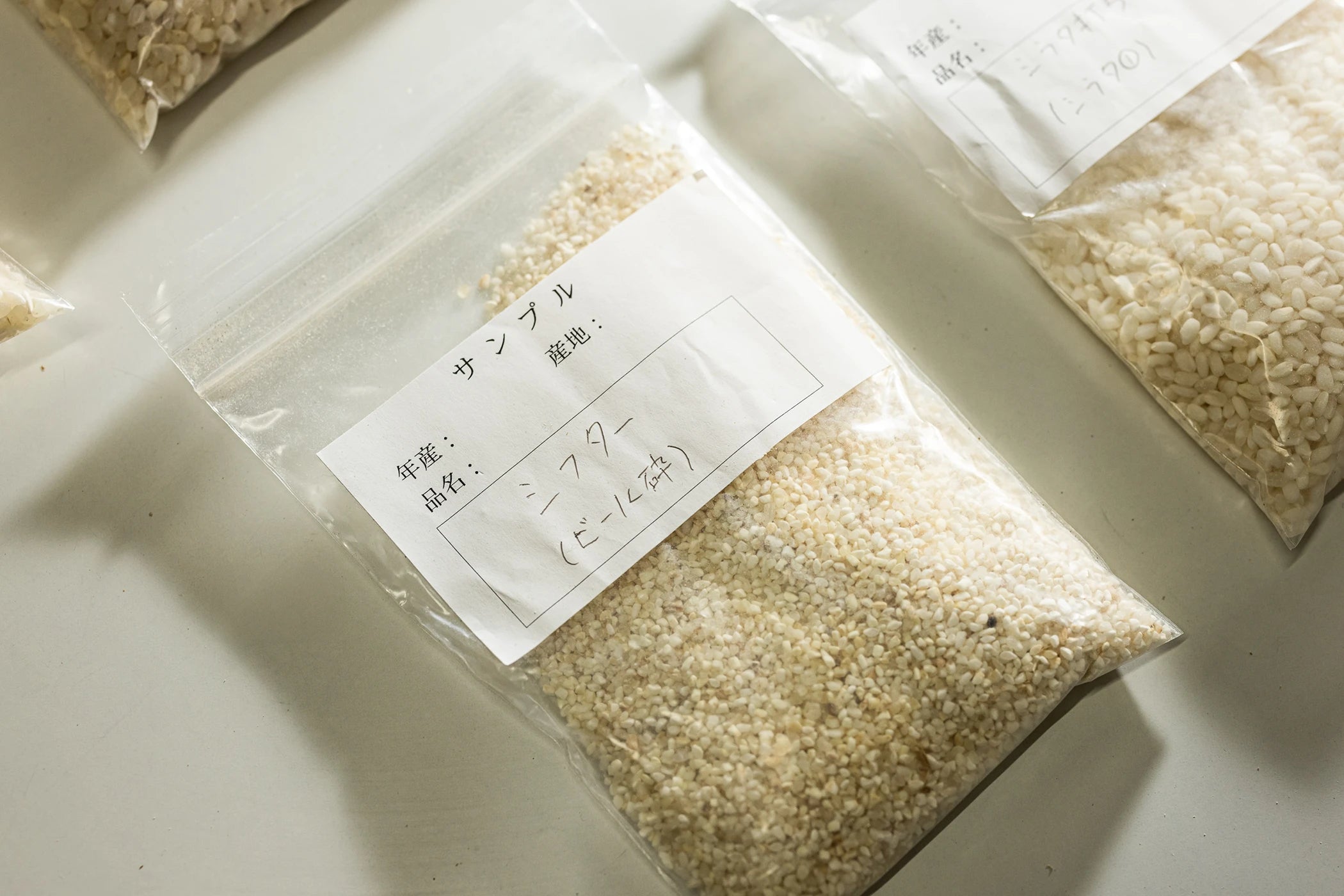 Koshihikari rice grain samples in labelled plastic bags at Kanegae farm in Kumamoto.