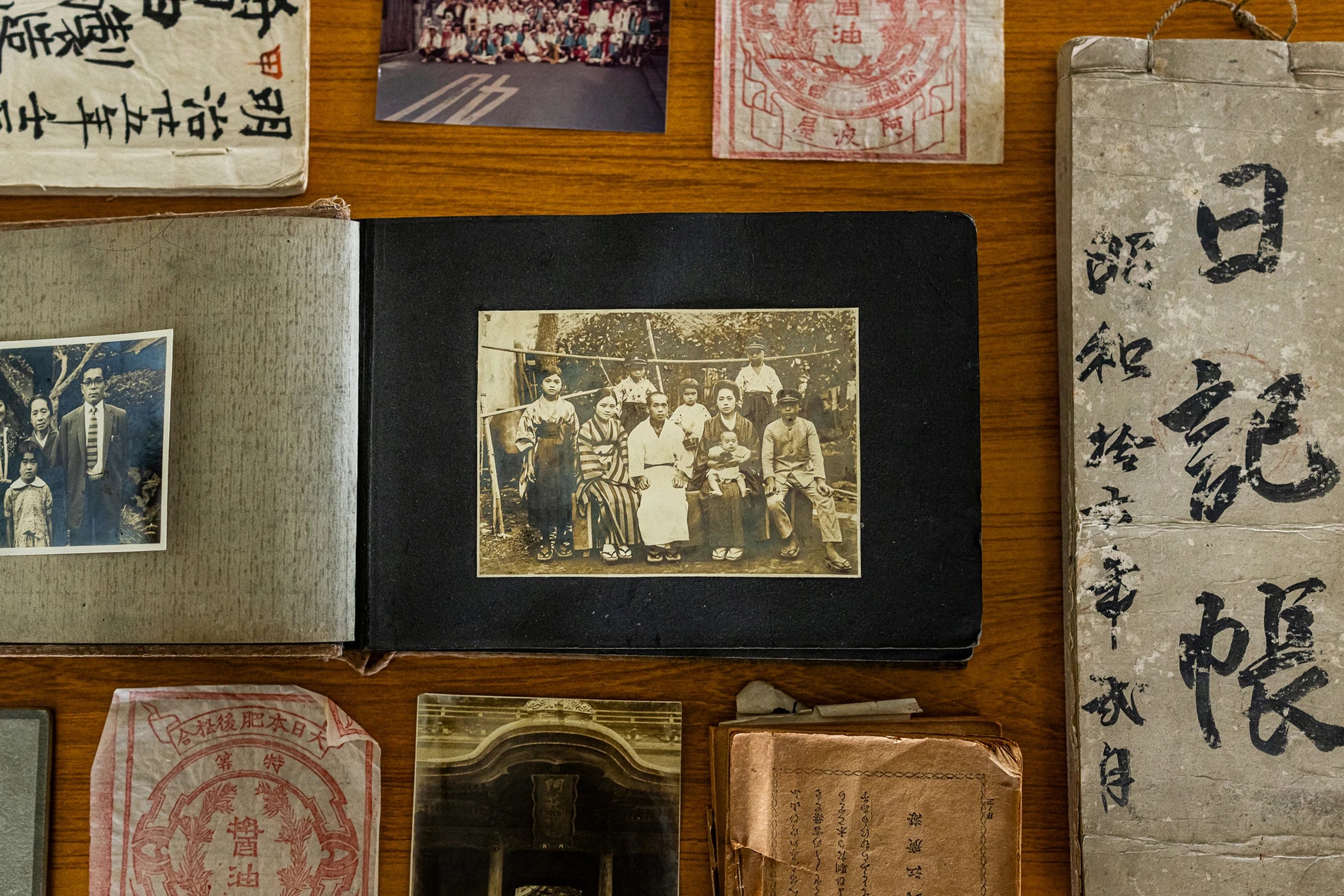 Vintage photo album with old photographs and documents on a wooden surface.