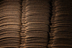 A close-up of tightly stacked, curved layers of pressed material used in shoyu production.