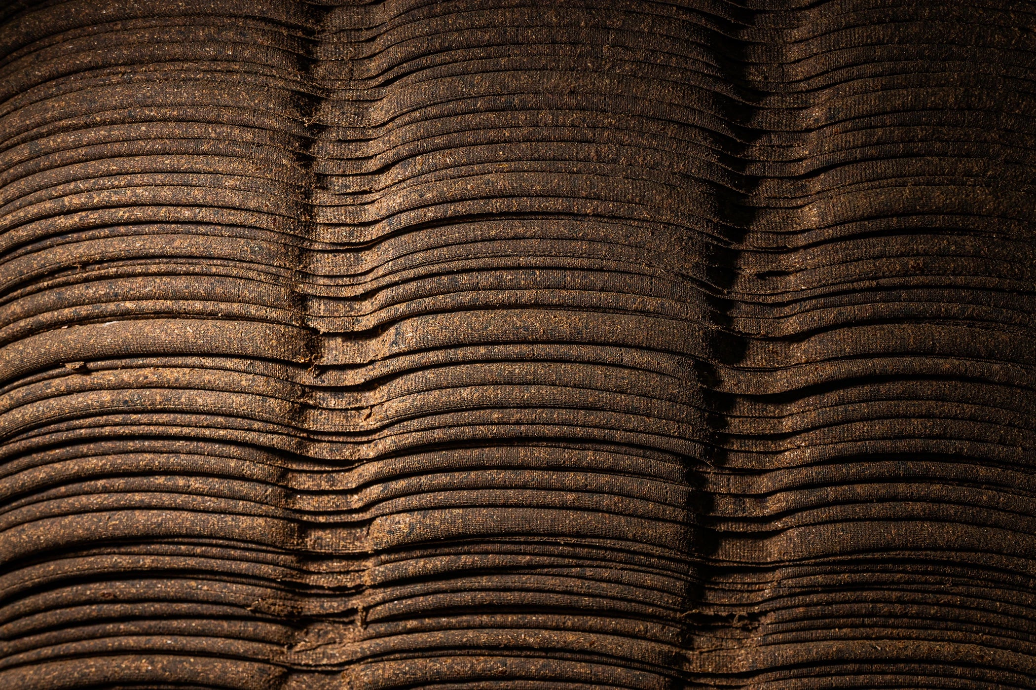 A close-up of tightly stacked, curved layers of pressed material used in shoyu production.
