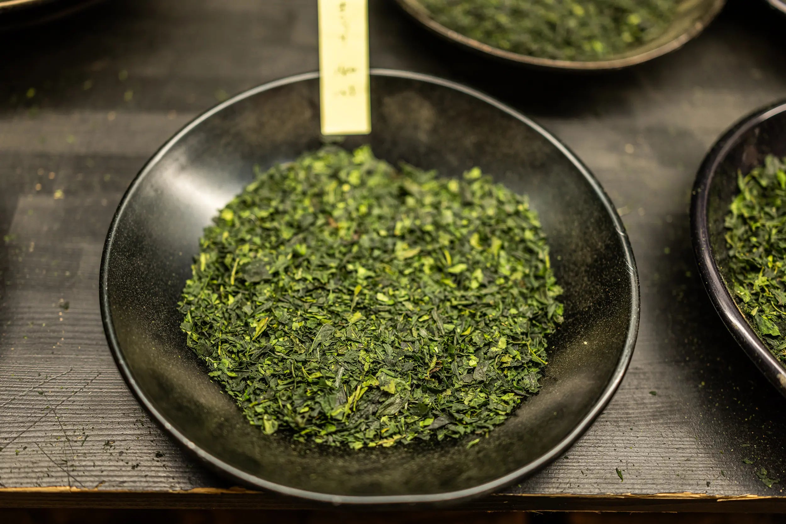 Green tencha in a black bowl on a dark surface