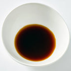 White bowl filled with dark liquid on a white background