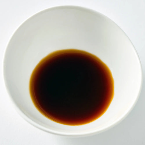 White bowl filled with dark liquid on a white background