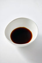 White bowl filled with dark liquid on a white background