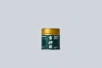 Container of matcha with gold lid and dark green label with white text on a light gray background