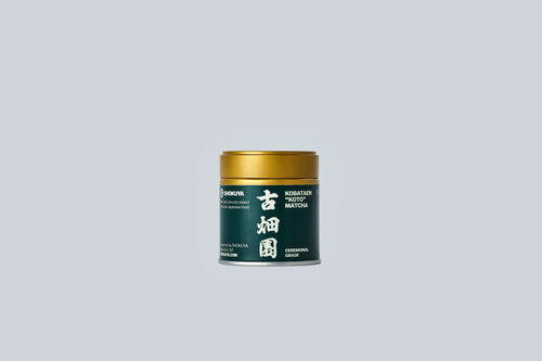 Container of matcha with gold lid and dark green label with white text on a light gray background