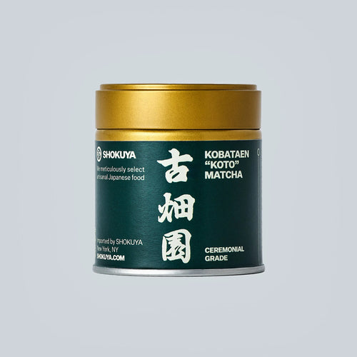 Container of matcha with gold lid and dark green label with white text on a light gray background