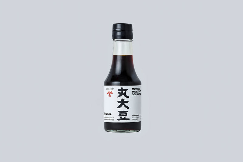 Bottle of soy sauce with a black cap on a light gray background