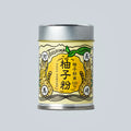 Small metal canister of Japanese yuzu powder from Oishi Farm centered on a light gray background, with a yellow illustrated label showing yuzu fruit and Japanese text.