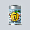 Small metal canister of Japanese yuzu salt from Oishi Farm centered on a light gray background, with a blue illustrated label showing yuzu fruit, fish, and Japanese text.
