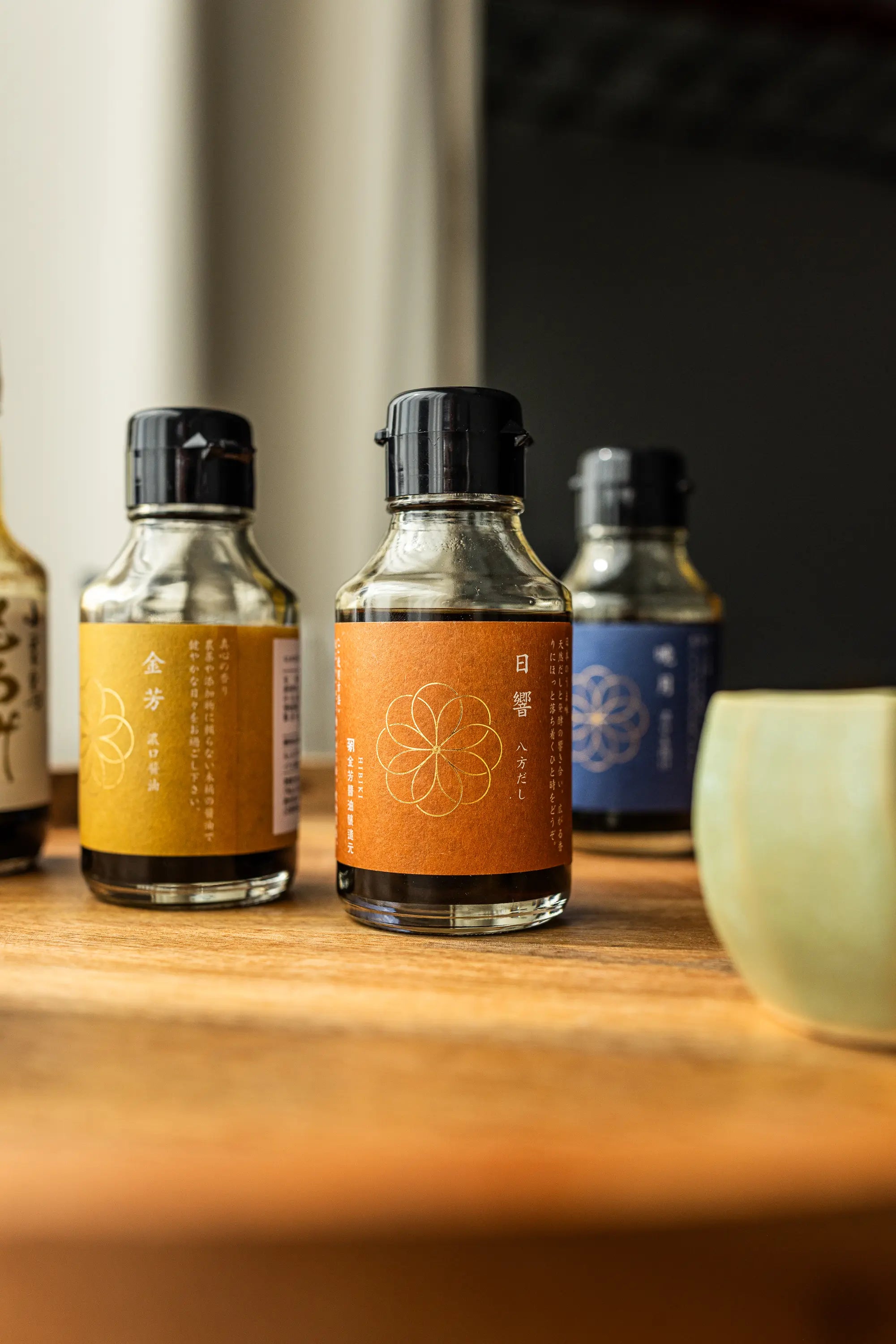 Three small bottles with labels on a wooden surface, with a blurred background.