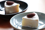 Slice of cake with an almond on a blue plate, with another slice in the background.